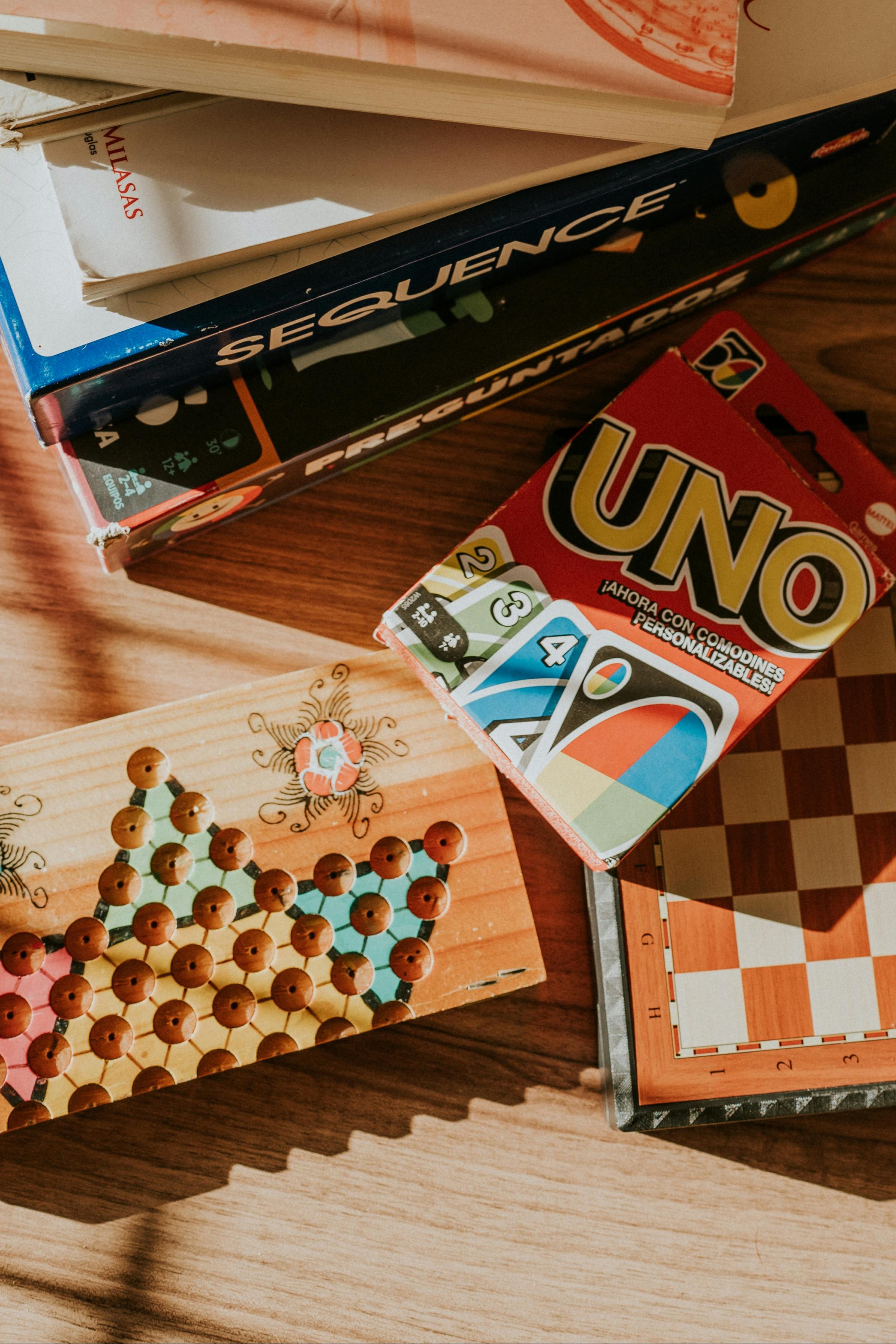 Stack of books and board game boxes on a wooden surface
